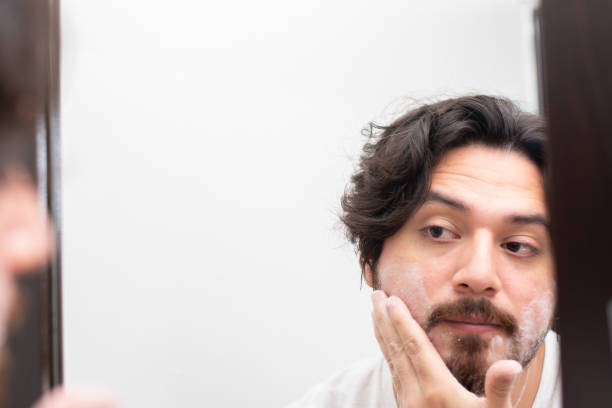 istock Portrait of man preparing with cream his beard to shave while looking his reflection in mirror 1495147514