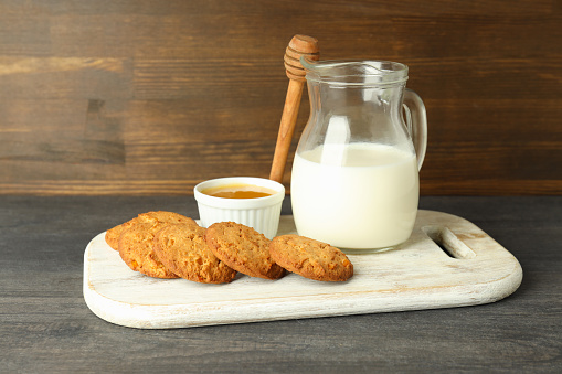 Milk, honey and pumpkin cookies on gray wooden table.