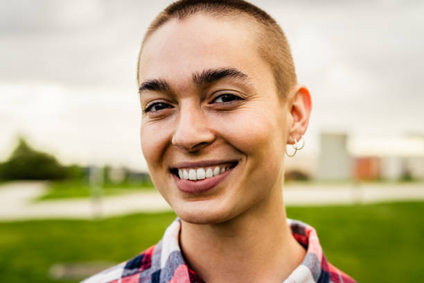Happy young woman with shaved head posing and smiling in front of camera stock photo