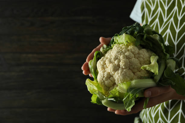 istock Woman in apron holds fresh cauliflower, space for text 1495154239