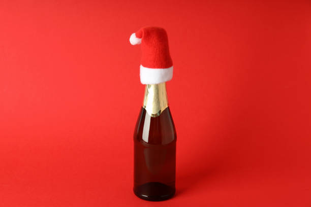 istock Champagne bottle with Santa hat on red background 1495155056