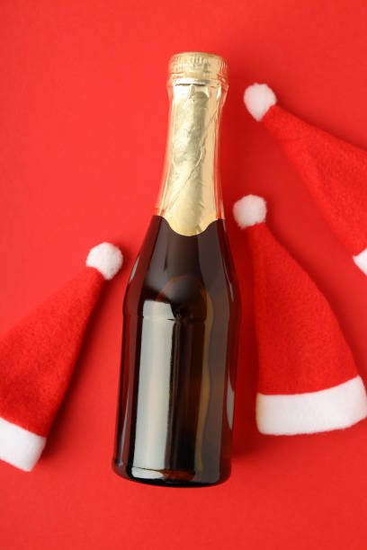 istock Champagne bottle and Santa hats on red background 1495156180