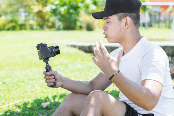 istock Young Latino man creating a video vlog, explaining the progress of his summer trip, holding the camera with his hand. 1495158493