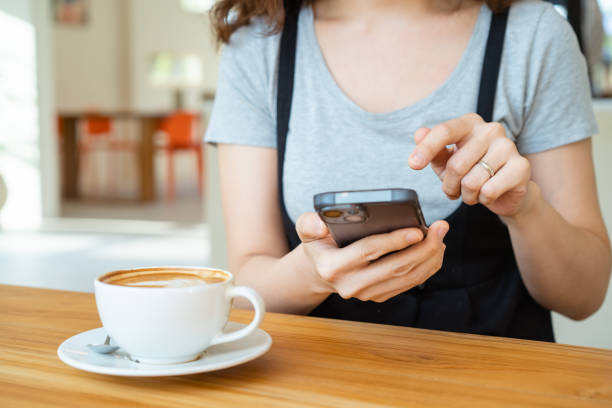 istock Woman drinking coffee and using smartphone in coffee shop. 1495158734