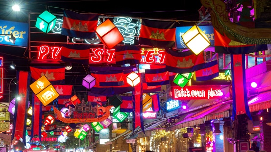 Siem Reap, Cambodia, December, 2018. vibrant flags of Cambodia and decorative garlands hanging over Pub Street in Siem Reap. Festive street lights and decorations set the stage for a lively ambiance.