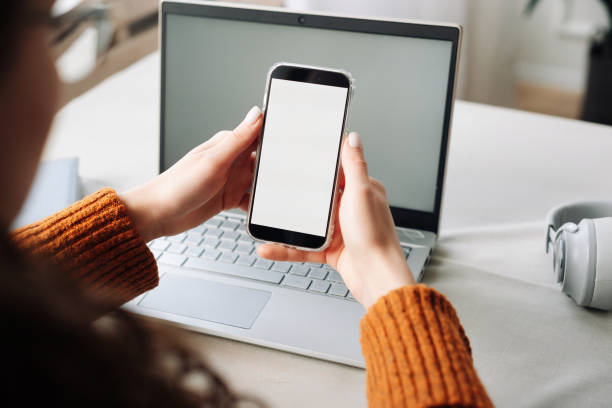 over shoulder view of woman holding mobile phone with white blank mock up cellular screen applications working using cell phone. cellphone display mock up for advertising apps concept. - news of the world imagens e fotografias de stock