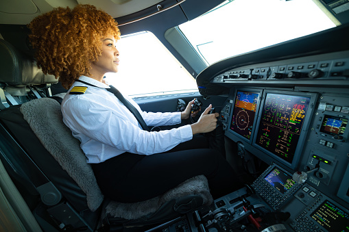 An African American pilot with curly hair steering a private jet.