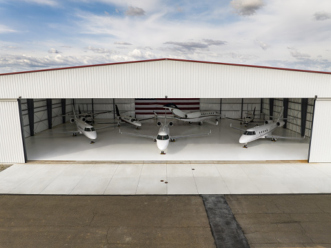 Seven private planes parked inside a massive hangar bearing the United States flag.\n\nThis drone shot was taken with full permission and co-operation of the airport staff and the pilots of the aircraft.