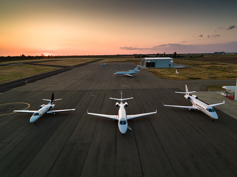 Four private jets parked on the runway, shot at sunset.

This drone shot was taken with full permission and co-operation of the airport staff and the pilots of the aircraft.