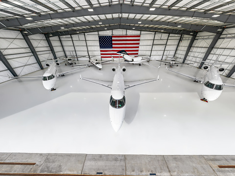 Seven private planes parked inside a massive hangar bearing the United States flag.\n\nThis drone shot was taken with full permission and co-operation of the airport staff and the pilots of the aircraft.