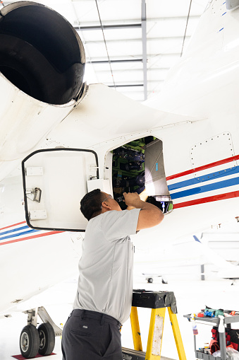 An airplane mechanic working on a private jet inside the hangar of a small general aviation airport in California.