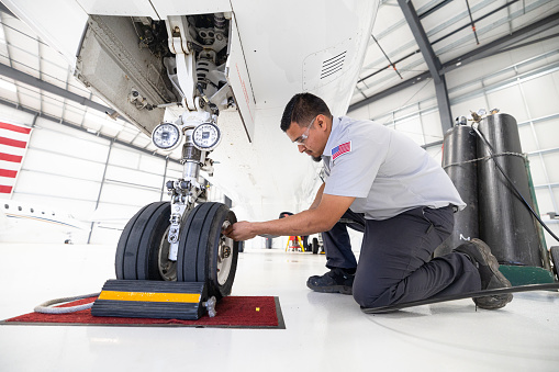 An airplane mechanic working on the wheels of a private jet inside the hangar of a small general aviation airport in California.