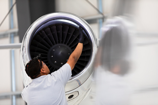Airplane Mechanic Checking Jet Engine Of Private Plane