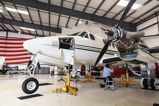 A mechanic working on one wing of a private jet inside the hangar of a small general aviation airport in California.