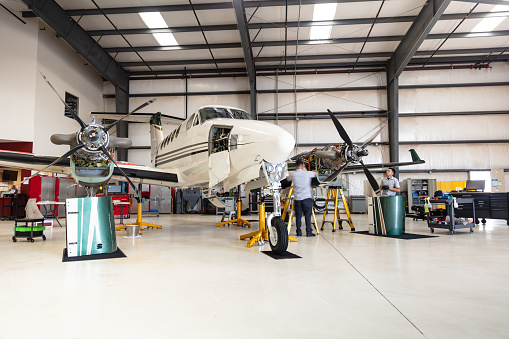 A turboprop plane undergoing maintenance inside the hangar of a small general aviation airport in California.