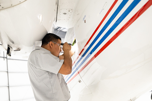 An airplane mechanic working on a private jet inside the hangar of a small general aviation airport in California.
