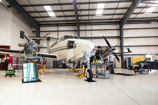 A turboprop plane undergoing maintenance inside the hangar of a small general aviation airport in California.