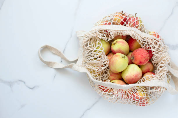 draufsicht auf äpfel in einem umweltfreundlichen schnurbeutel auf weißem hintergrund. - burlap fruit apple freshness stock-fotos und bilder