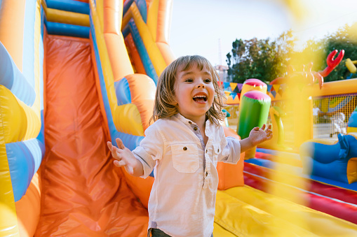 Happy little kid having fun in inflatable castle playground.