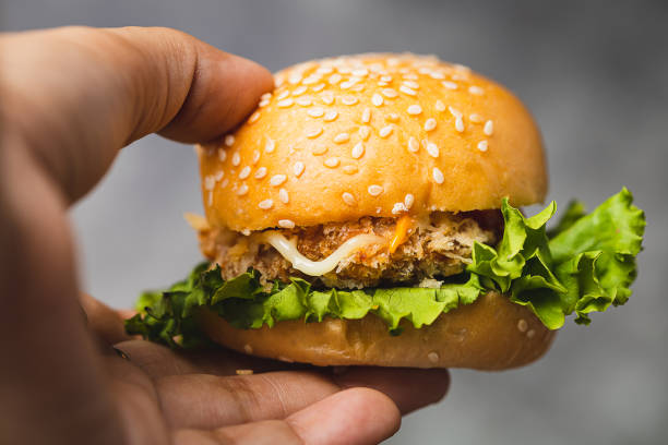 istock Hand holding a delicious hamburger with dark background 1495167342