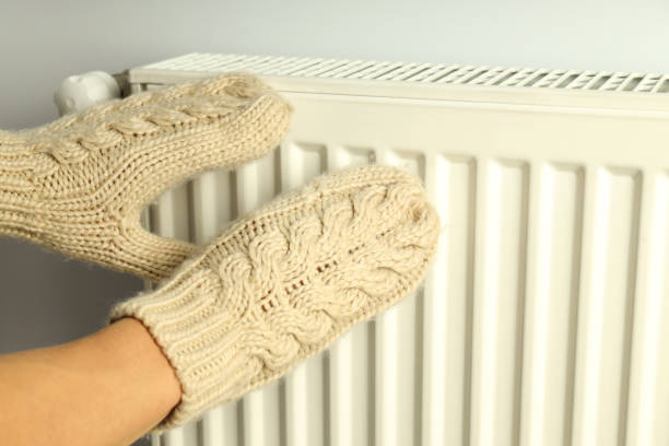istock Female hands in mittens keep hands near radiator 1495168136