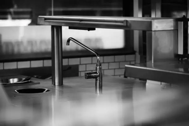 A stainless steel countertop kitchen sink with a matching industrial-style faucet in a professional kitchen