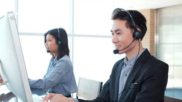 istock Young Asian male customer support phone operator with headset working in call center. Young man using headset and computer in modern office 1495170742
