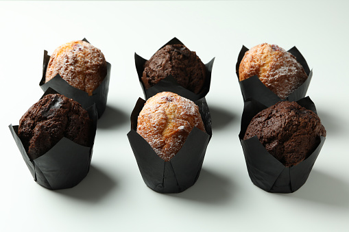 Chocolate muffins on white background, close up.