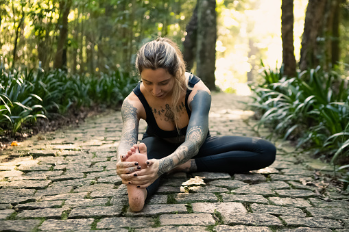 portrait of young brazilian woman, wearing black sportswear, doing yoga outdoors