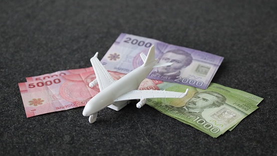 stacked chilean banknotes and a white plane on the table