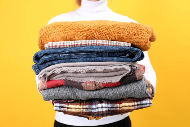 istock Woman holds winter clothes on yellow background 1495177762