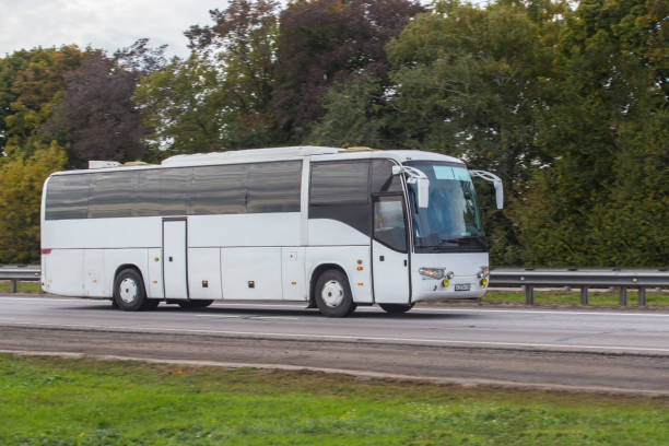 un bus touristique se déplace sur une route de campagne - driving a car photos et images de collection