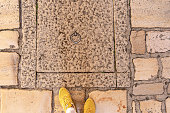 Yellow Sneakers Dressed Feet on Old Stone Cobbled Street