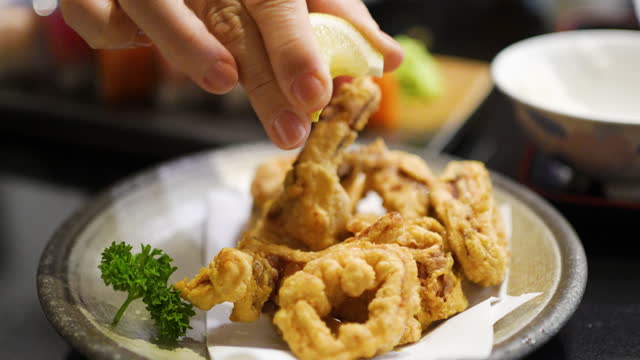 Squeezing a Piece of Lime Calamari crispy fried on the dish