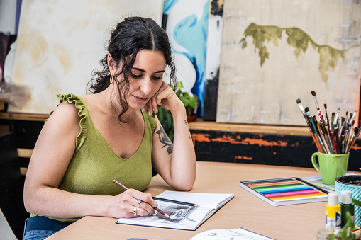 Mid adult woman drawing/painting on a notepad at home