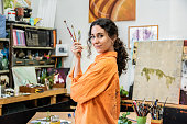 Portrait of a mid adult woman holding a set of paint brushes at home