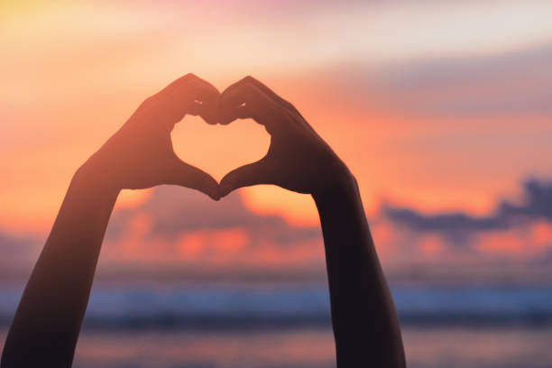 istock Hands forming a heart shape with sunset silhouette 1495189707