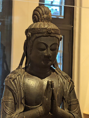 Honolulu - April 1, 2022:  Serene Buddha sculpture of a female figure with Prayer hands hands.