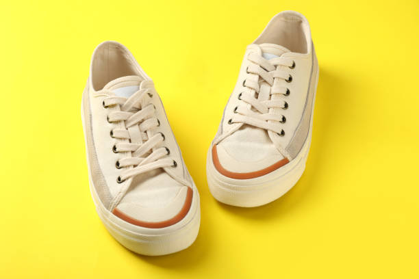 istock Pair of beige sneakers on yellow background 1495194046