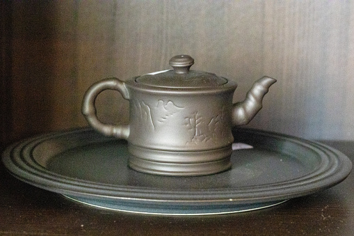 it's tea time, tray with teapot and cup; brown background and intimate lighting
