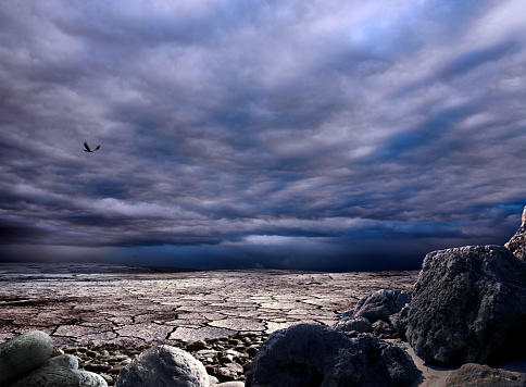 Conceptual image of dried and cracked landscape over cloudy and sunny sky