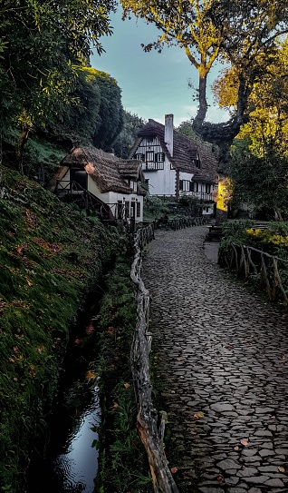 A scenic view of a stone paved path with rustic cottages. Queimadas Forest Park, Madeira.