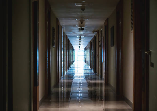 istock Dark long corridor in hotel with many doors and light in end from big window 1495202778
