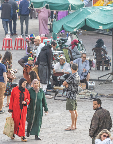 Women wearing the hijab near snake charmers at Djemma el Fna Square in Marrakesh, Morocco