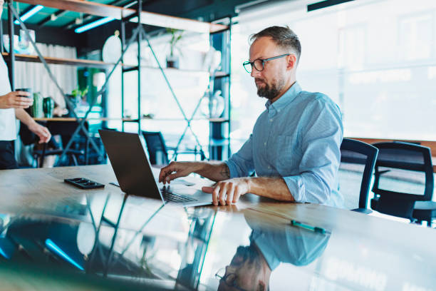 istock Young adult man working in coworking using laptop 1495205290