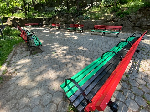 A group of benches painted in the Pan-African colors of red, black and green in the Drummers Circle in Marcus Garvey Park in Harlem, New York City