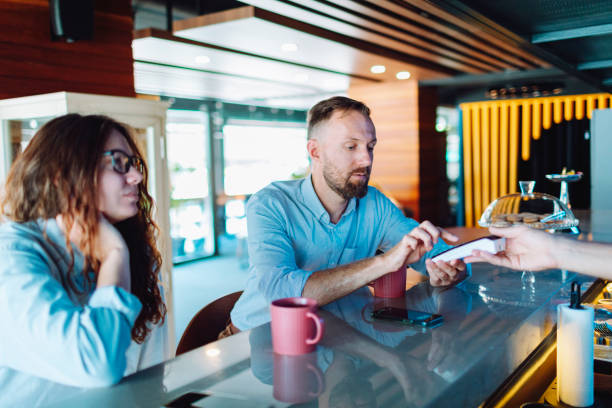 istock Young adult man paying for coffee at cafe using smartphone 1495207702