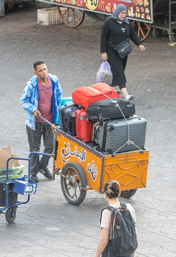 Porter (carroser) at Djemma el Fna Square in Medina District of Marrakesh, Morocco, with people in the background.
