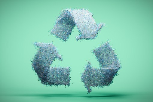 Recycling symbol made from plastic bottles on light green background.