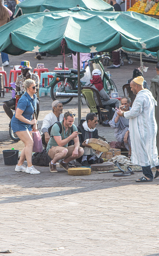 Tourists photographing Egyptian cobras near Snake Charmers at Djemma el Fna Square in Medina District of Marrakesh, Morocco